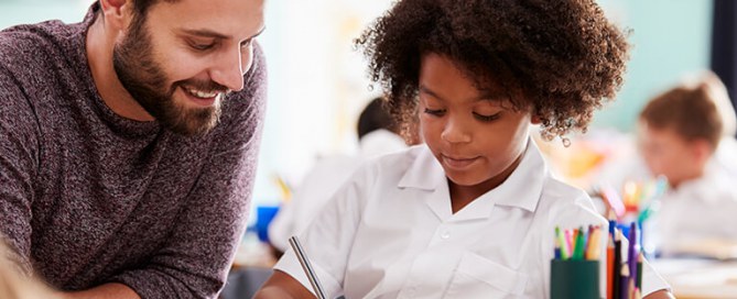 Male teacher teaching a student in uniform